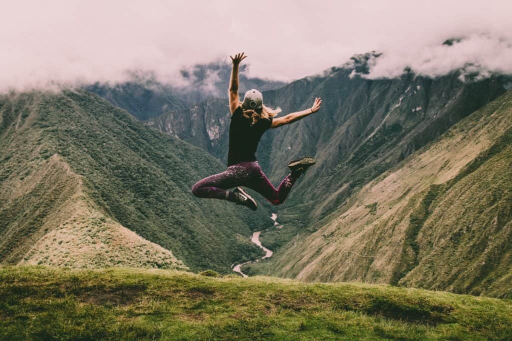 Active lifestyle - woman jumping on green mountains