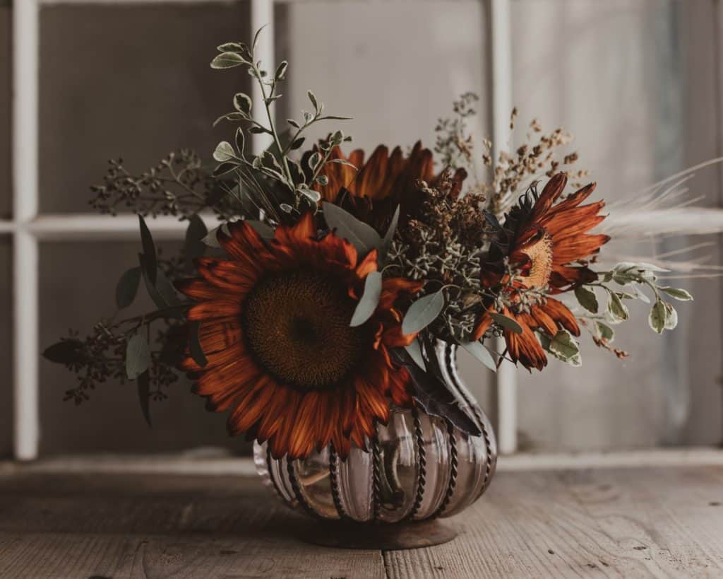 Fall cleaning - beautiful fall flower arrangement on a wooden surface in front of a window.