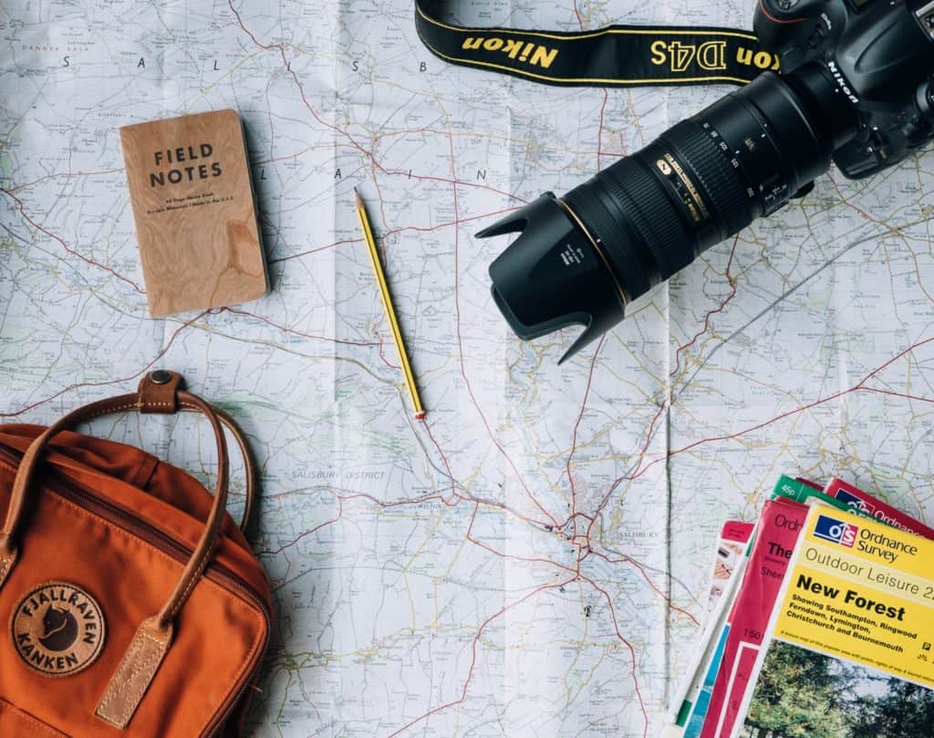 flat lay photography of camera, book, and bag and other travel items
