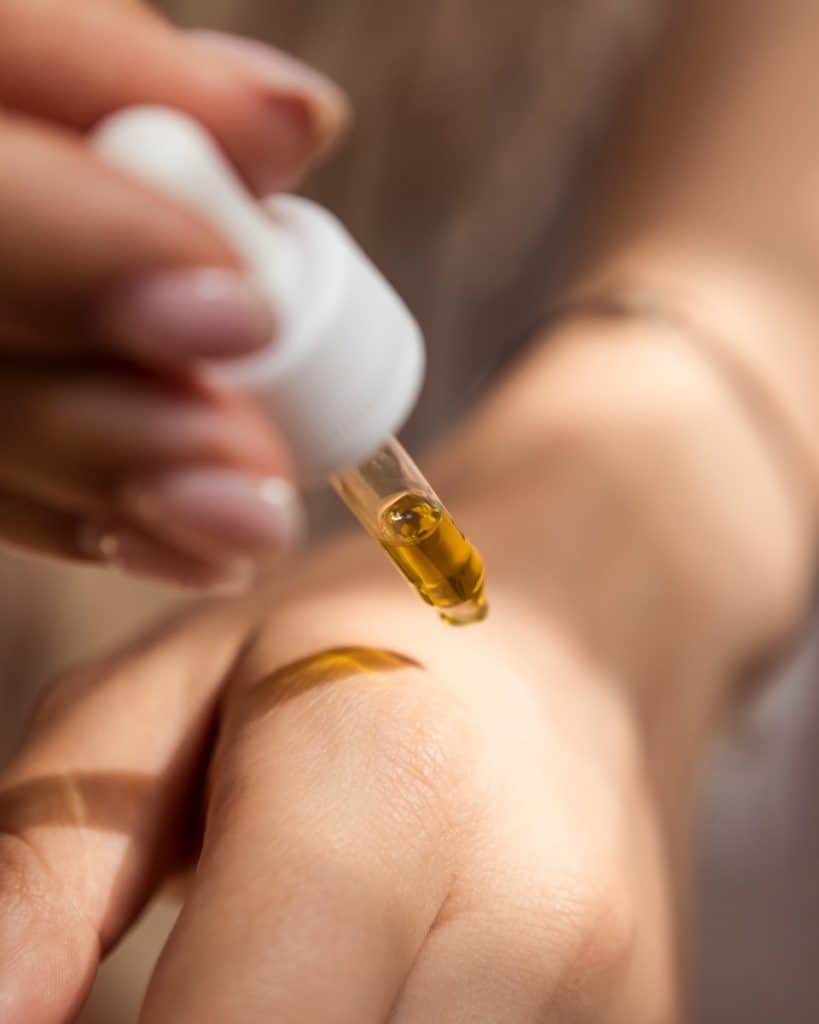 person holding dropper with skincare products