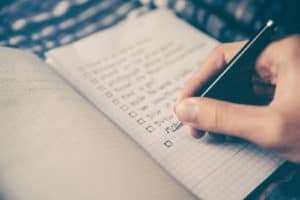 person writing bucket list on book in preparation for time-blocking