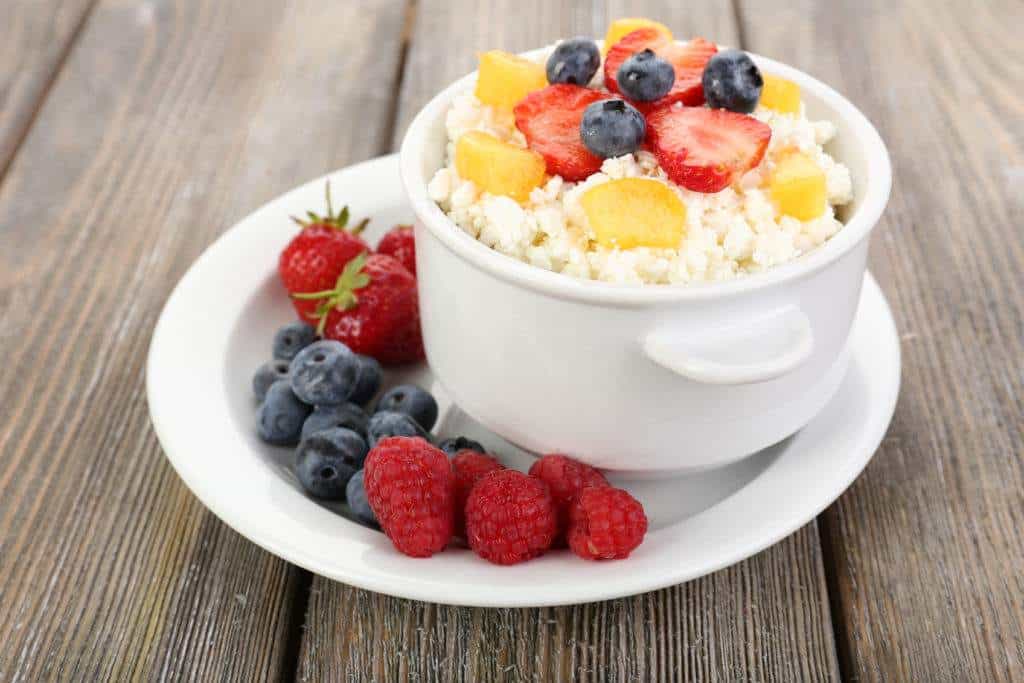 Snack ideas for work - Cottage cheese with fruits and berries in bowl on wooden table