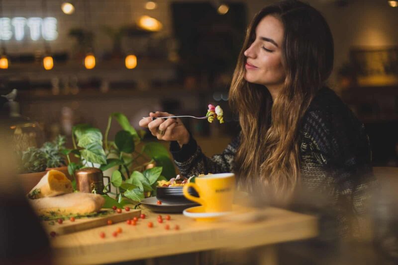 woman holding fork in front table learning how to eat intuitively