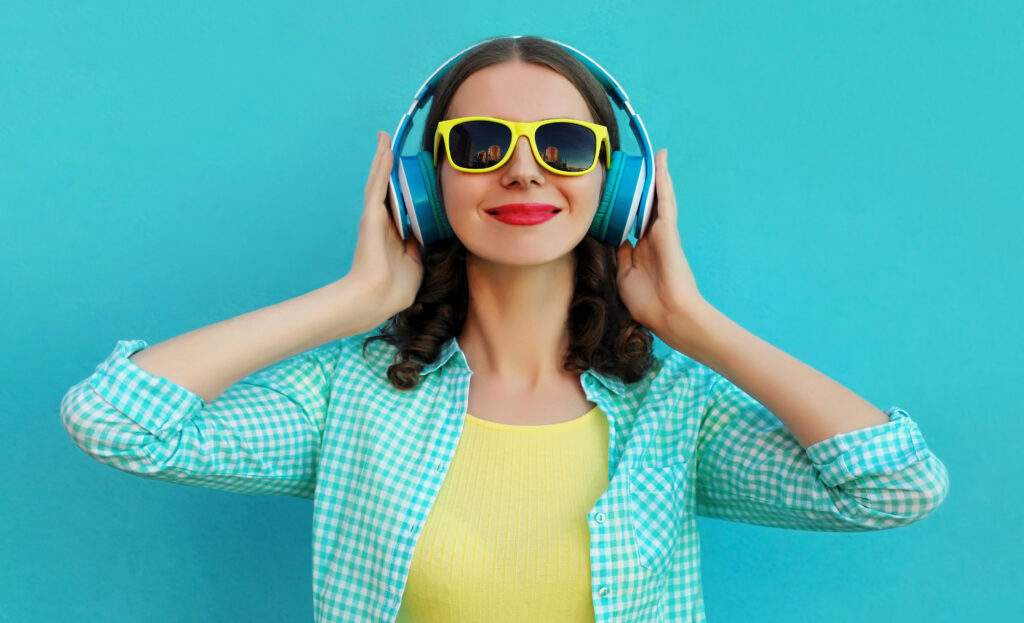 Portrait of happy young woman with wireless headphones listening to self-development podcasts on a blue background