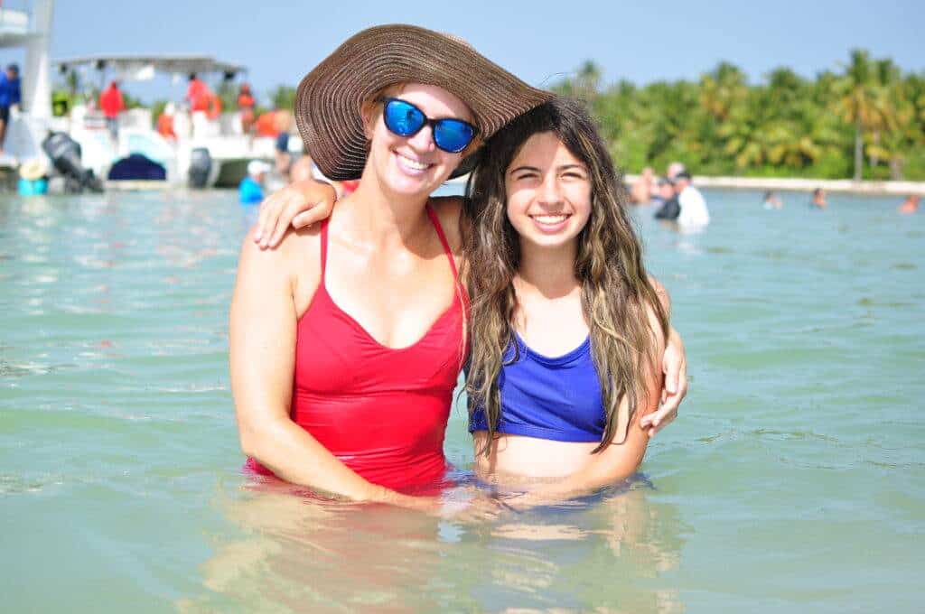 A mother and daughter standing in the blue ocean with people standing behind them