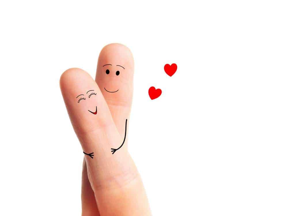 Two fingers wrapped around each other. The fingers have faces and the finger behind has arms and is lovingly holding the finger in front. There are two hearts next to them illustrating a happy relationship.