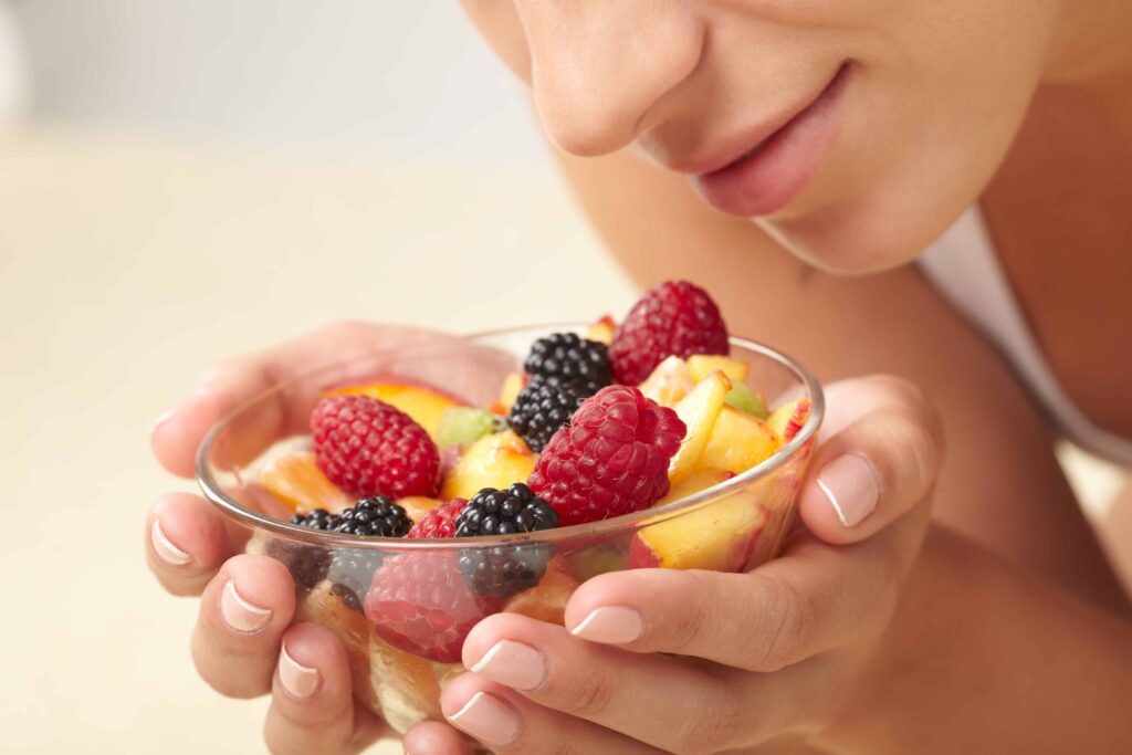 Women enjoying a fruit salad, looking at the food, smelling it which is one. of many great mindful eating tips