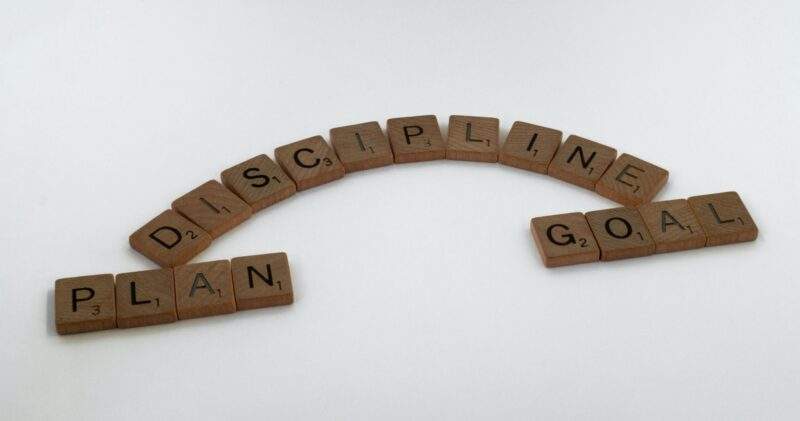 Scrabble letters form the words plan, discipline, and goal. this is the formula for how to stay disciplined.