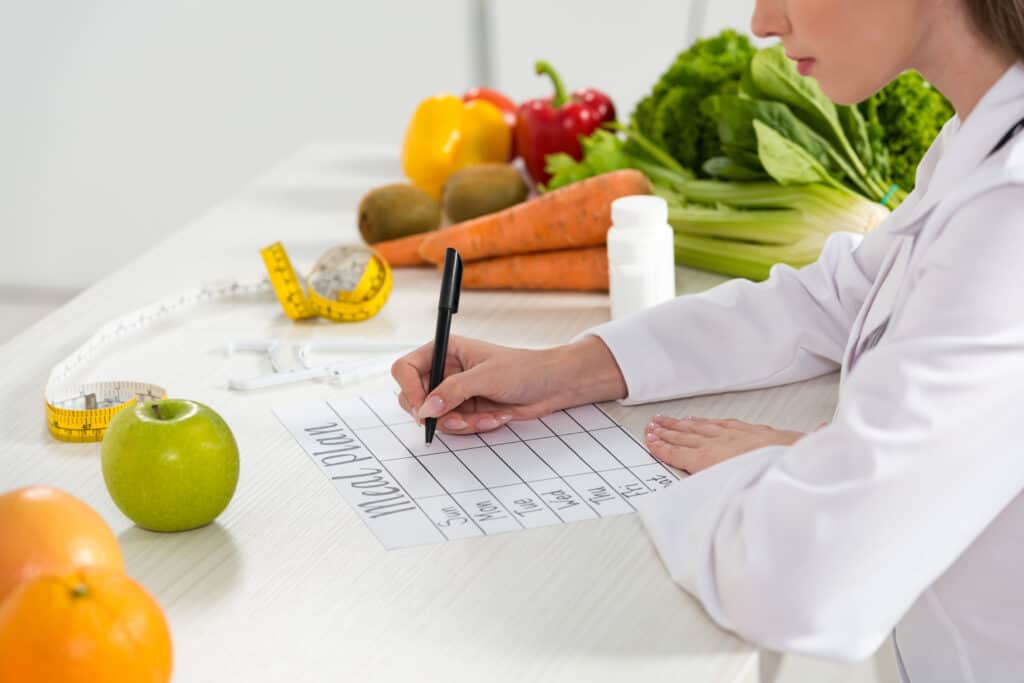 A woman in a white shirt writing a healthy family meal planning