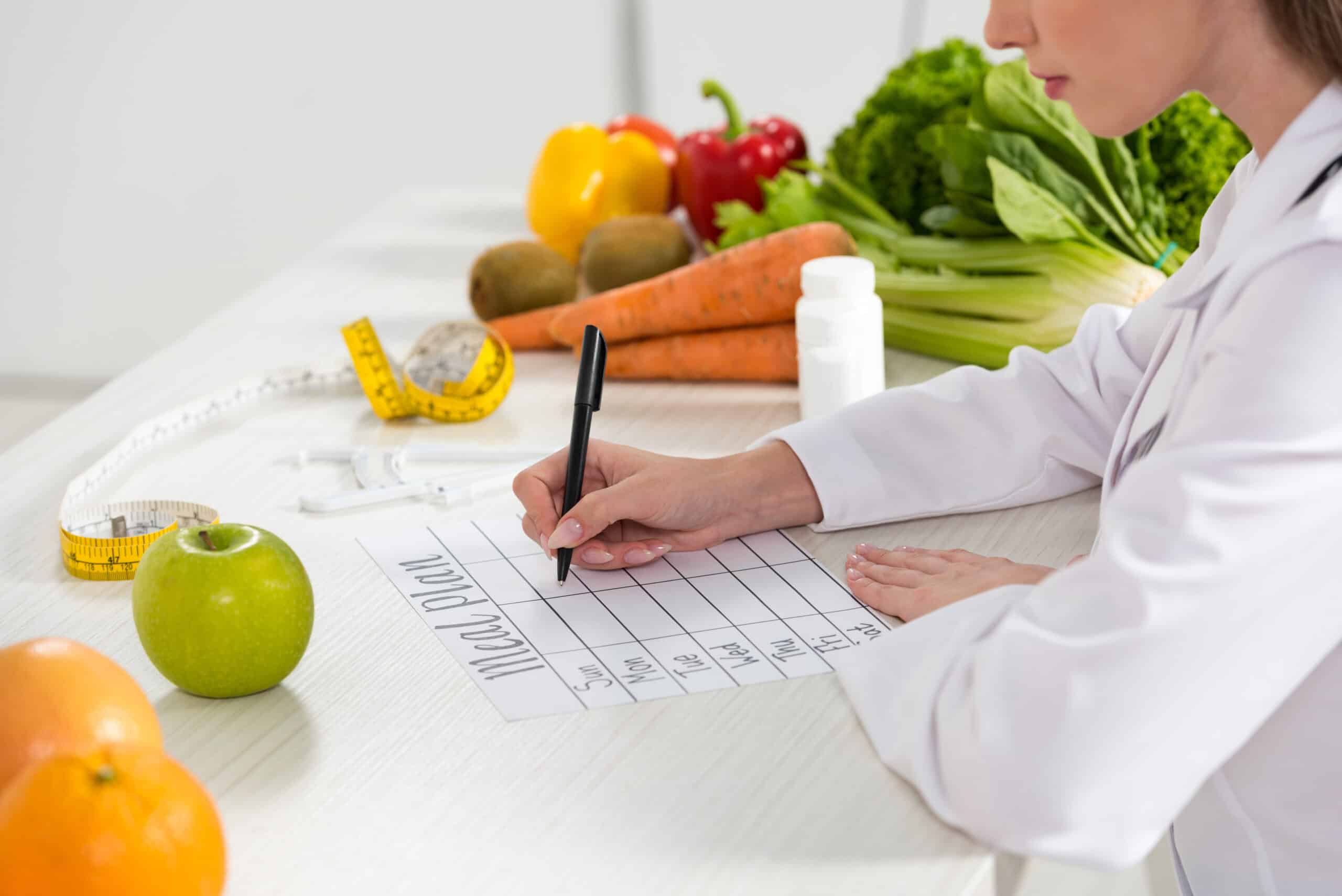 A woman in a white shirt writing a healthy family meal planning