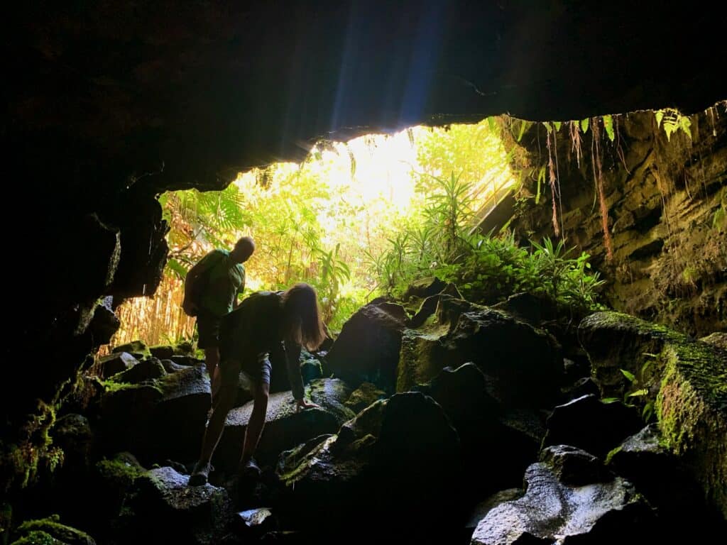 Two people walking down into a the Kaumana caves in Hilo Hawaii.