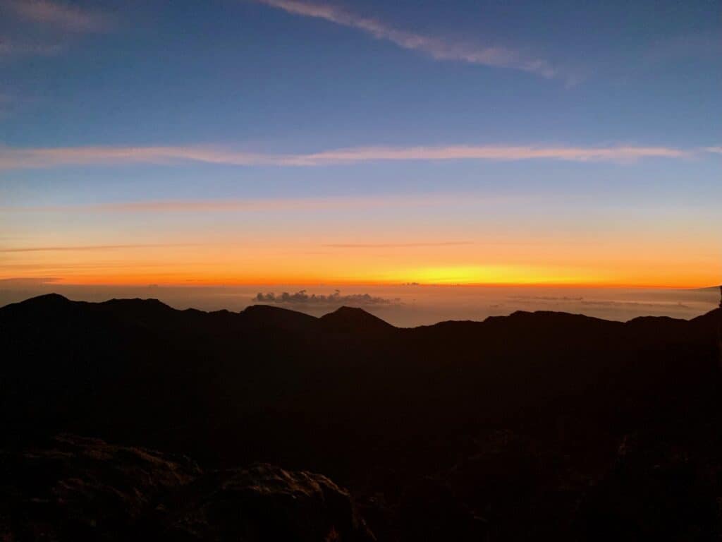 The sun rising above clouds from the Haleakala dormant volcano in Maui.