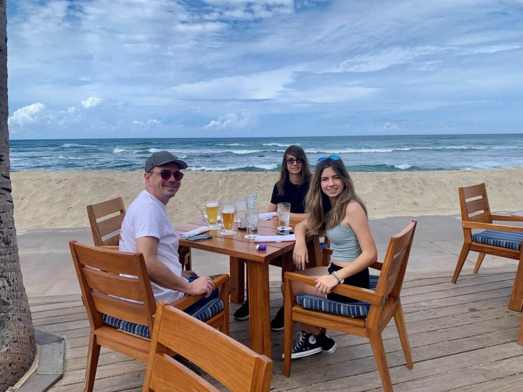 A man and 2 teenagers having lunch by the Ocean on the Big Island, Hawaii.