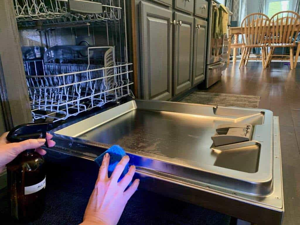 Woman cleaning the inside door edge of a dishwasher