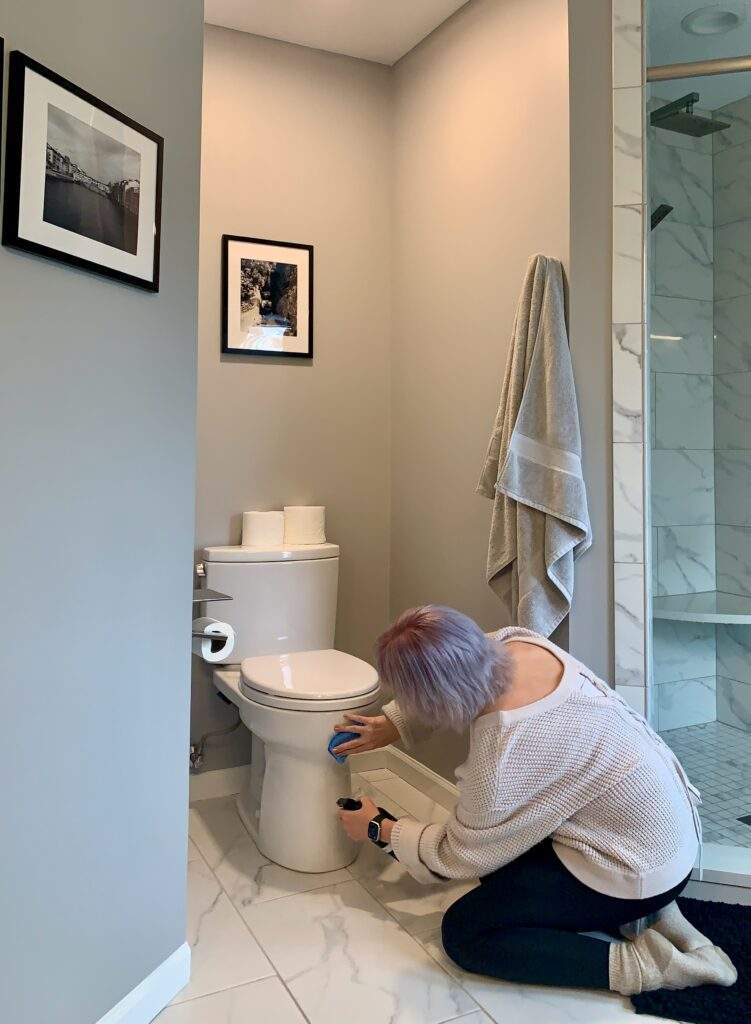 Woman cleaning the base of a toilet as things to clean that are often forgotten