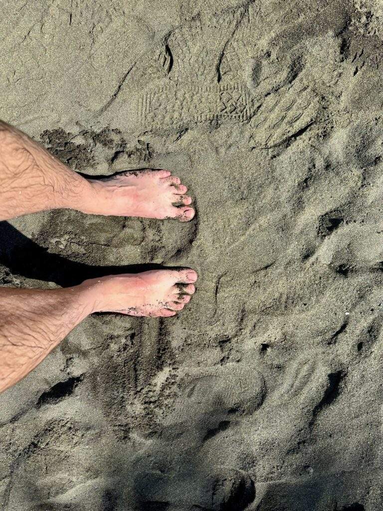 What to do on the big island black sand beach with an image of 2 feet on black sand