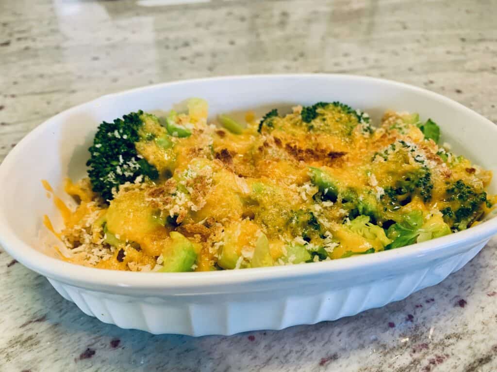A white ramequin with quinoa, broccoli and cheese.