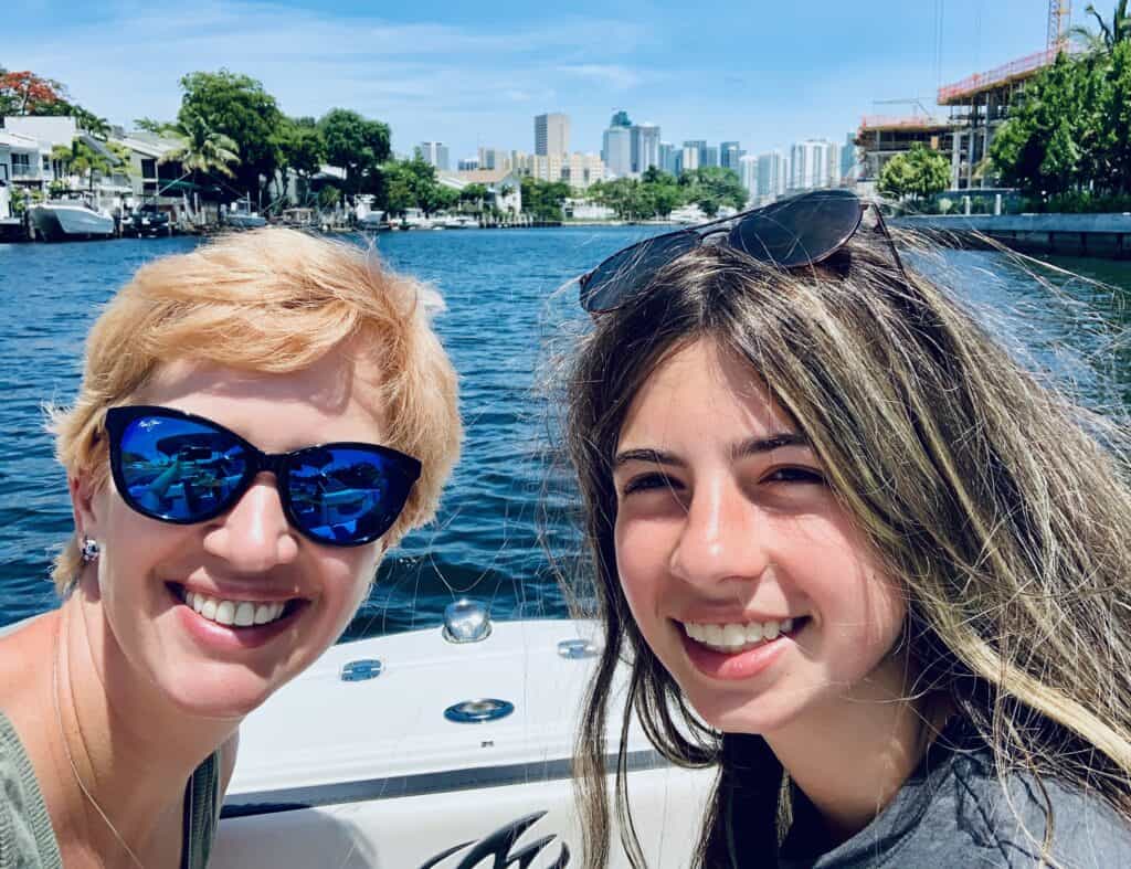 A woman and a teenage girl smiling on a boat making the best during unfortunate air travel disruptions