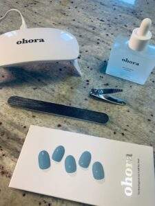 Everything needed for an at-home Ohora manicure: gel sticker kit, gel sticker remover, nail file, nail clipper, and curing lamp.