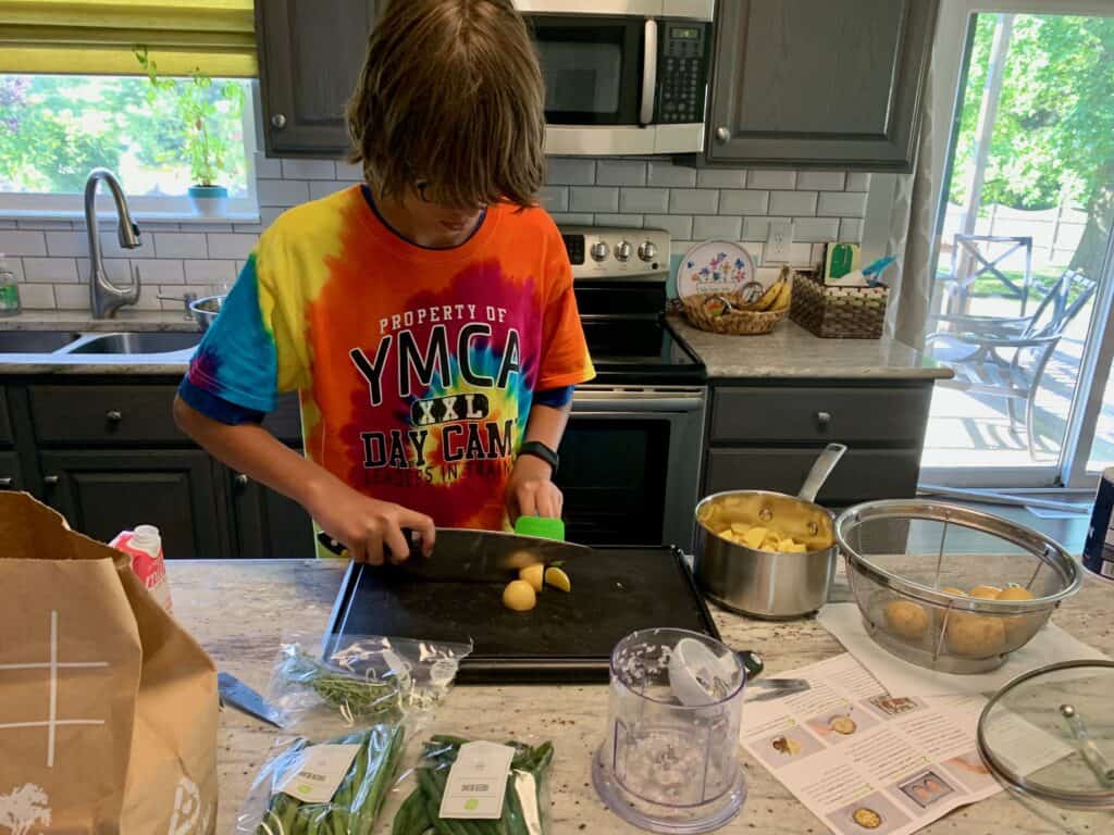 A teenager makes dinner because cooking is an important thing to know before university.