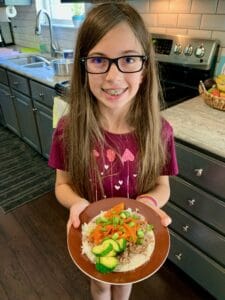 A teenage girl holding a plate of food she made herself