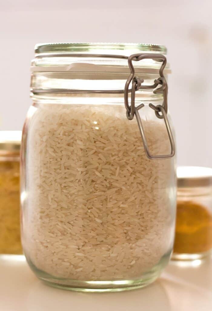 clear glass jar with white rice inside which is a pantry staples list item