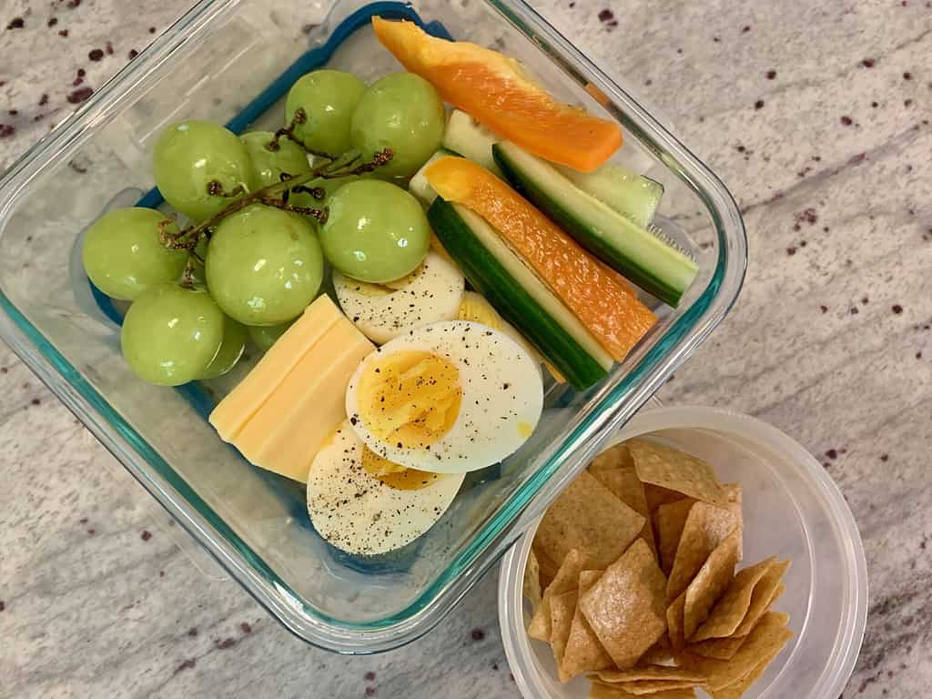 A fun snack lunch with hard-boiled eggs, cheese, peppers, cucumbers, grapes and crackers.