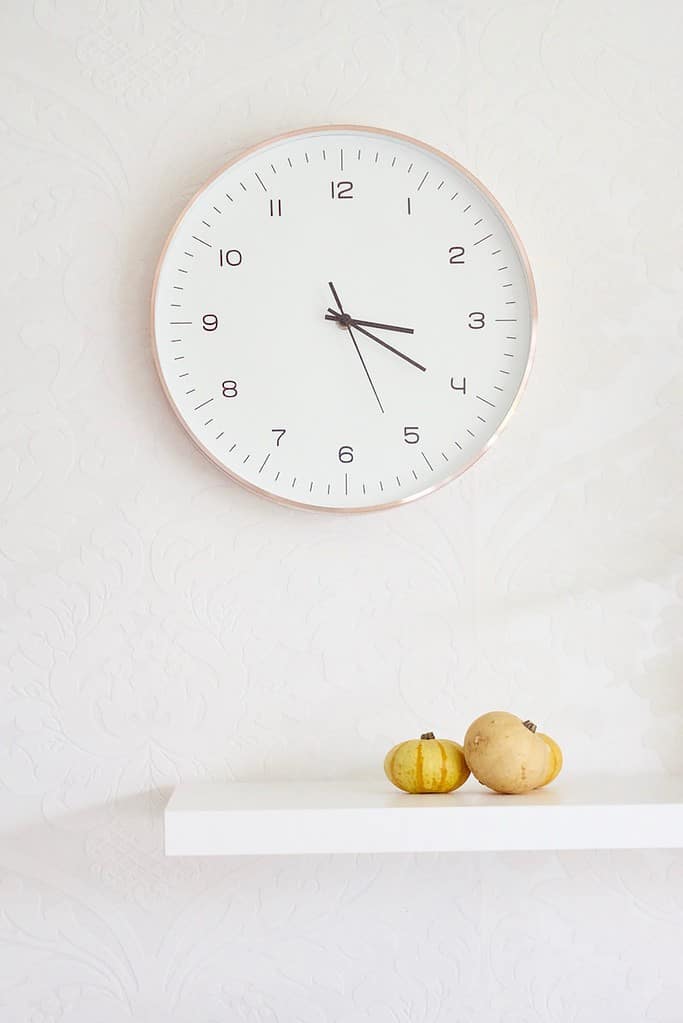two pumpkins on table below wall clock - intermittent fasting healthy habits