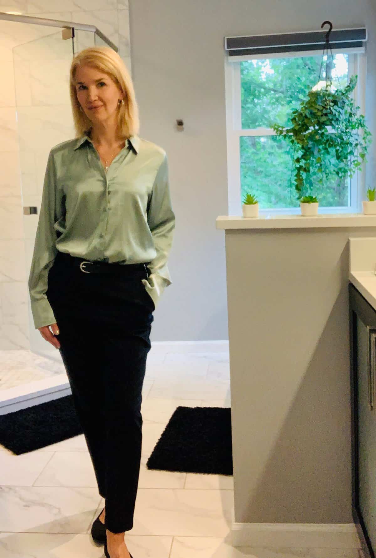 Woman wearing black trousers, black flats and a green sage satin button up shirt - professional fall look