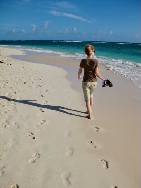 A woman walking on a white sand beach. How to pick an all-inclusive resort tips.