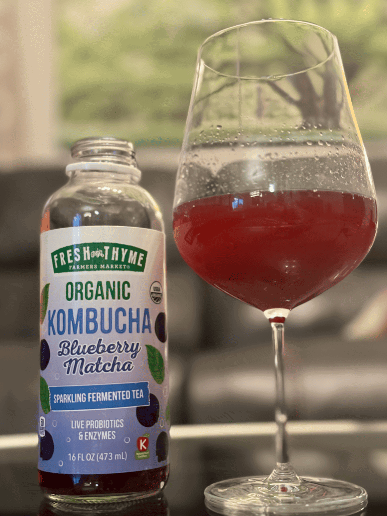 A wine glass with Kombucha in it and a bottle of kombucha next to it. A great dry January tip.