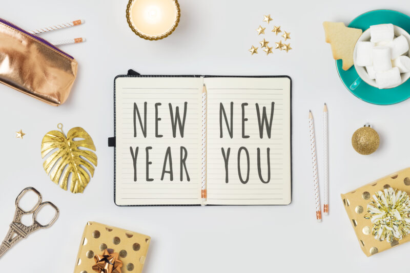 New Year resolutions concept with notepad and gift boxes on whit