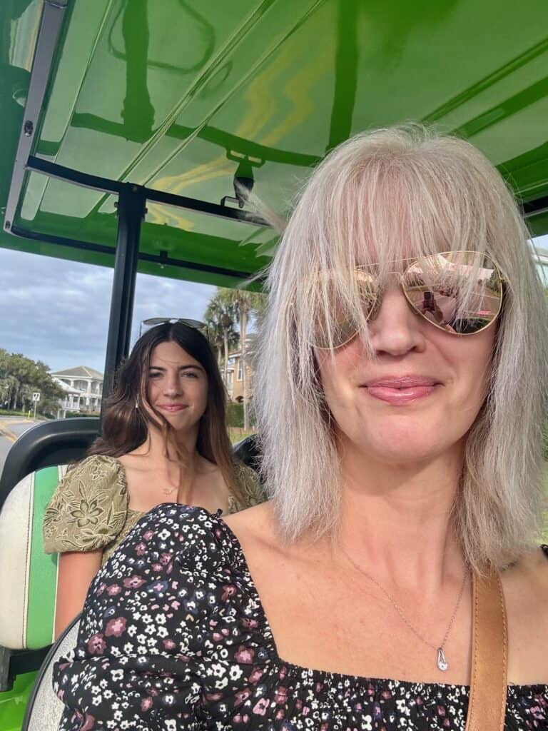 A woman and a girl on a green golf cart.