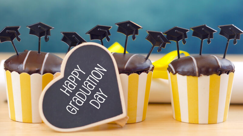Cup cakes with yellow wrapper and a heart sticker that says Happy Graduation Day